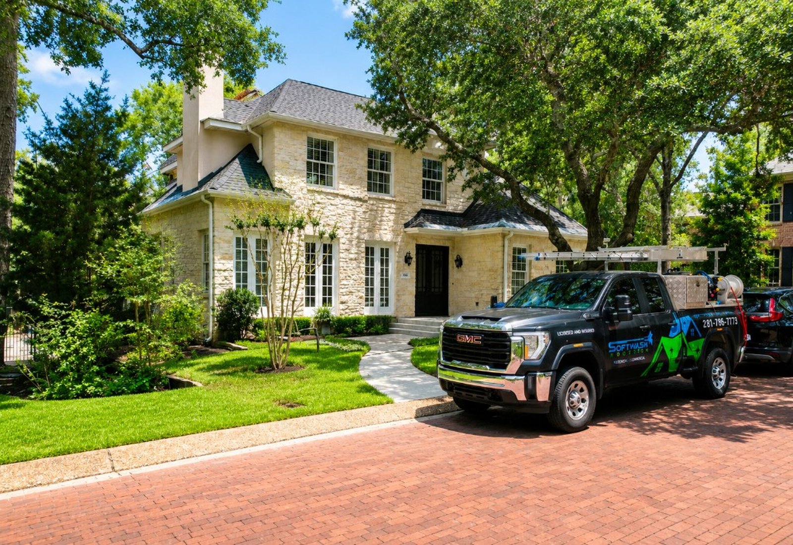 Service truck parked at a stone home after exterior cleaning
